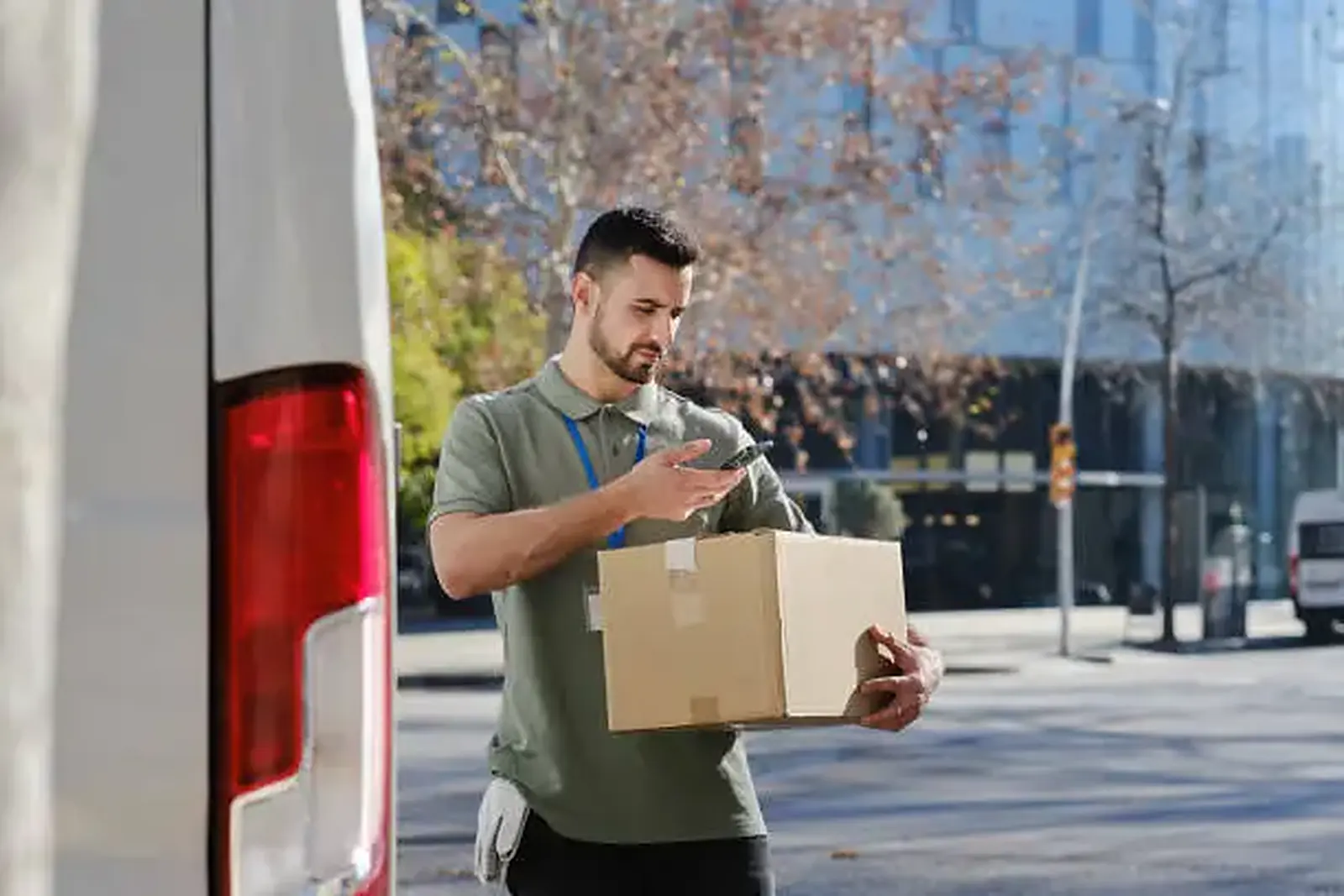 Кур'єр Truck-Taxi скануює посилку біля вантажного буса Кур'єр Truck-Taxi скануює посилку біля вантажного буса