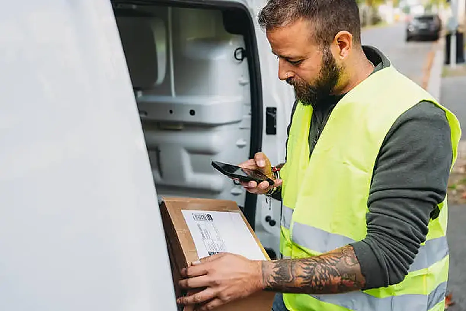 Водій Truck-Taxi звіряє посилку з накладною на телефоні Водій Truck-Taxi звіряє посилку з накладною на телефоні